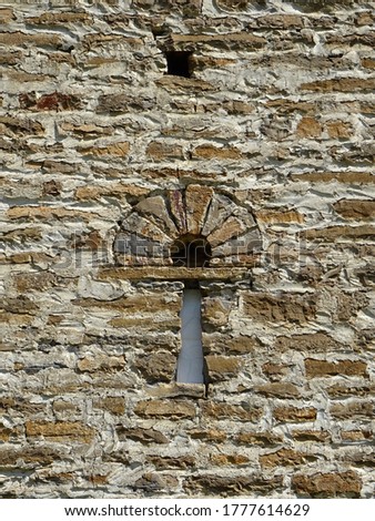 Arrowslit shape window with horseshoe arch. Mozarab Pre-Romanesque or Romanesque Church of San Bartolome de Gavin. 10th-11th century. Serrablo Region in Aragon. Spain.                               