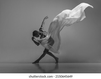 Art and beauty of male body. Black and white portrait of graceful muscled male ballet dancer dancing with fabric, cloth isolated on grey studio background. Grace, health, strength - Powered by Shutterstock