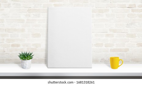 Art Canvas Mockup On Desk Leaning Against The Brick Wall. Plant And Coffee Mug On Desk. Scene Creator With Separated Layers