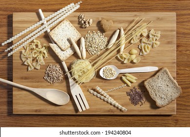 Art Composition Of Pasta, Grains,  Whole Grain Bread, Wooden Kitchen Set Placed On Wooden Cutting Board And Wooden Background