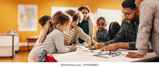 Art and creativity in an elementary school class. Teacher shows his students how to draw using a colouring pencil in a classroom. Primary education and child mentorship. - Shutterstock ID 2291038863