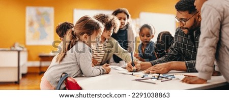 Art and creativity in an elementary school class. Teacher shows his students how to draw using a colouring pencil in a classroom. Primary education and child mentorship. Foto stock © 