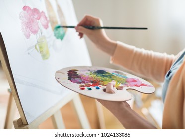 art, creativity and people concept - close up of artist with palette and brush painting still life on paper at studio - Shutterstock ID 1024133086