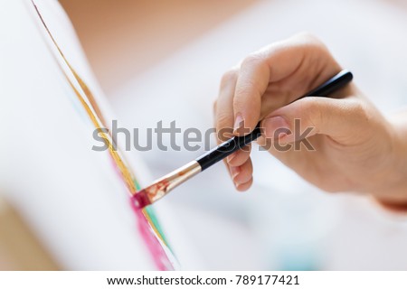 art, creativity and people concept - hand of artist with brush painting picture