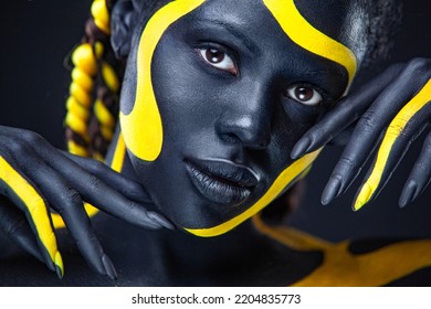 The Art Face. Close-up Portrait. Black And Yellow Body Paint On African Woman. Abstract Creative Portrait. Bright Fashion Makeup On The Girl.