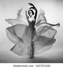 Art Fashion Studio Photo Of Beautiful Elegant Woman In Blowing Dress. Flying Dress. Freedom Concept. Fashion Style Of Flowing Dress