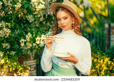 Art Happy red hair woman holding porcelain white cup in hands fantasy retro lady drinking tea, girl princess having tea beauty romantic face. summer garden tree park vintage style straw hat on head - Powered by Shutterstock