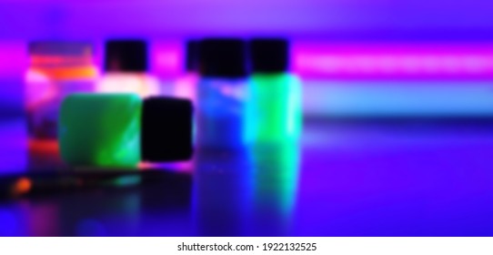 art jars with neon fluorescent fluorescent glowing in the dark paints under ultraviolet light blurred background defoxus horizontal wide banner free space for text