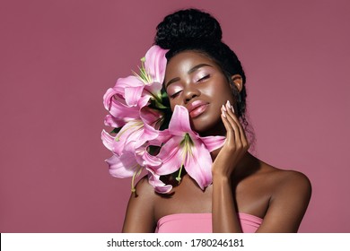  Art Make Up. Fashion Beauty Portrait Of Young African American Model Touching Face With Posing With Lily Flowers Against Pink Background. 