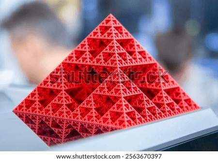 Art object printed on 3D printer from red melted plastic close-up. Model of pyramid created on 3D printer from plastic. 3D Printing technology. Additive progressive technology. New modern technologies