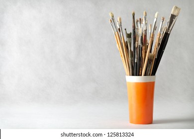 Art paint brushes in cup with empty room for text