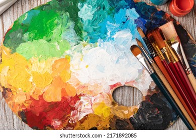 art palette with colorful mixed paints and paintbrushed - Shutterstock ID 2171892085