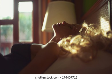 Art photo of beautiful blonde in bed in the sun
