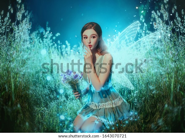 Art photo fantasy pixie butterfly. young fairy with\
glow wings holds bouquet flower. dark blue backdrop fabolous night\
Firefly star glitter light. Fingers show sign silence. cute face,\
makeup red lips