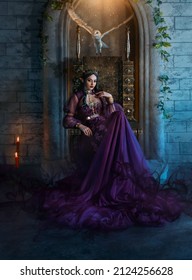 Art photo fantasy woman evil elven queen sits on throne, dark magic around purple long dress. Sexy witch elf girl, pointy ears. Gothic Brunette vampire princess, golden crown. Barn owl flutters wings.