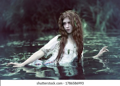 Art photo of a forest drowned woman in the dark muddy water of a swamp