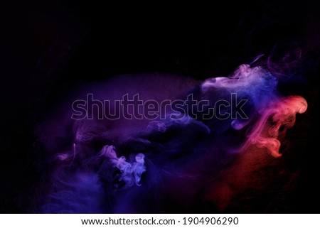 Art photo of smoke moves on black background. Beautiful swirling colorful smoke.