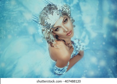  Art portrait attractive snow queen. Fantasy blond woman. creative handmade crown polymer clay. Glamorous makeup. Fabolous Frozen. Backdrop winter falling snow. Cute face. Vintage white design dress