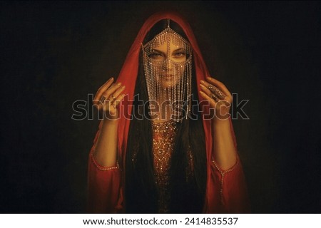 art Portrait Fantasy girl Mystery arabic woman in red long dress stands in desert long silk abaya dress. clothes gold Golden Mask chain Burka hide face Oriental Eastern style. Black studio night room.