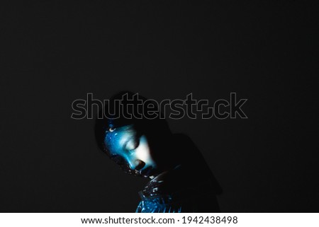 Art portrait. Soul harmony. Reincarnation destiny. Karma afterlife. Blue color peaceful Asian woman face silhouette with closed eyes abstract pattern light isolated on black copy space background.