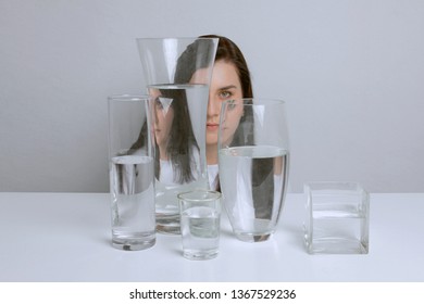 Art Portrait Of Young Attractive Woman. Distorted Reflection In Glass Vases With Water.