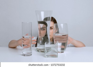 Art Portrait Of Young Attractive Woman. Distorted Reflection In Glass Vases With Water.