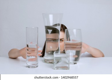 Art Portrait Of Young Attractive Woman. Distorted Reflection In Glass Vases With Water.