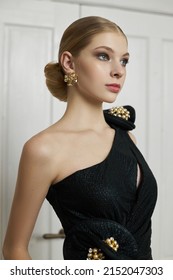 Art Portrait Of A Young Blonde Woman, Hair Bun. Beautiful Woman In Black Evening Dress. Perfect Evening Makeup On Face, Hairstyle. Fashion Studio Portrait Of Beautiful Elegant Woman In Black