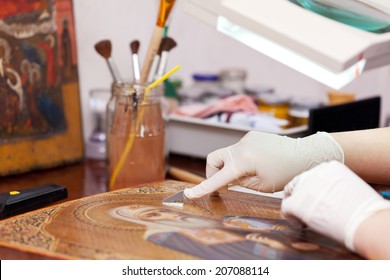 Art Restorer Working On The Old Icon With Spatula At Restoration Workshop