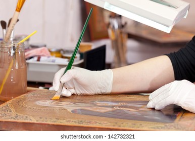 Art Restorer Works On Old Gilded Icon With Brush At Restoration Workshop