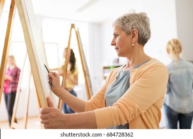 art school, creativity and people concept - happy senior woman artist with easel and pencil drawing picture at studio - Shutterstock ID 684728362