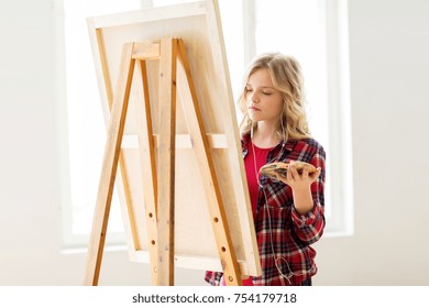 Art School, Creativity And People Concept - Student Girl Or Artist With Earphones, Easel And Palette Painting At Studio