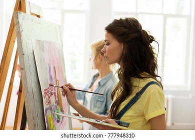 art school, creativity and people concept - woman with easel, palette and brush painting at studio - Powered by Shutterstock