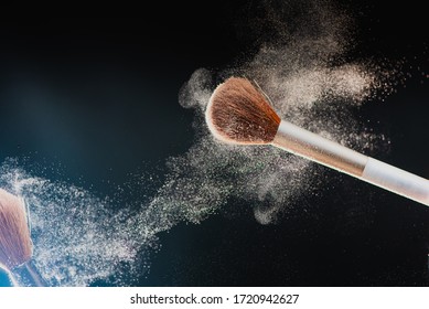 The art of visage. Horizontal closeup photo of two professional black makeup brushes with colored powder isolated on black background 