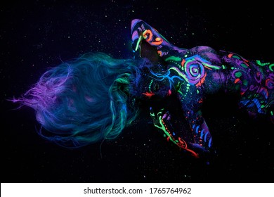 Art woman body art on the body dancing in ultraviolet light. Bright abstract drawings on the girl body neon color. Fashion and art woman
