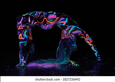 Art woman body art on the body dancing in ultraviolet light. Bright abstract drawings on the woman body neon color. Colored hair and face