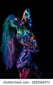 Art woman body art on the body dancing in ultraviolet light. Bright abstract drawings on the woman body neon color. Colored hair and face. Out of focus, noise