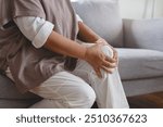 Arthritis is a chronic disease problem in elderly healthcare, Asian old female touching her leg feeling pain in her knee joint, and can