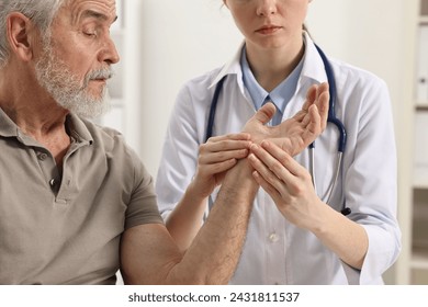 Arthritis symptoms. Doctor examining patient's hand in hospital - Powered by Shutterstock