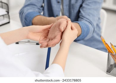 Arthritis symptoms. Doctor examining patient's wrist in hospital, closeup - Powered by Shutterstock