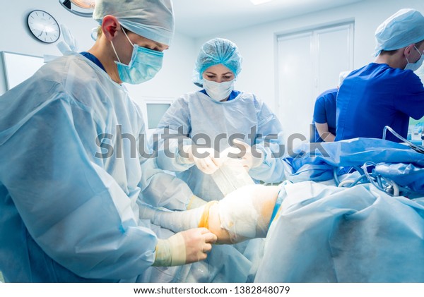 Arthroscope surgery. Orthopedic surgeons in\
teamwork in the operating room with modern arthroscopic tools. Knee\
surgery. Hospital\
background