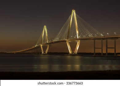 The Arthur Ravenel Jr. bridge illuminated against a darkening Spring sky.  The bridge carries eight lanes of traffic across the Cooper River, connecting Charleston and Mount Pleasant, SC, USA.   