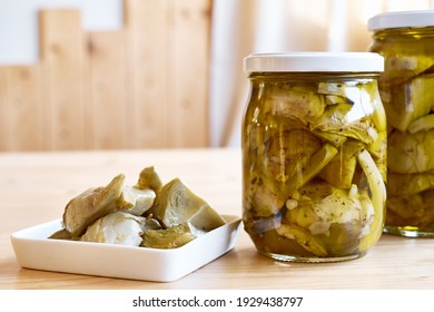 Artichokes hearts marinated with olive oil and herbs. Pickled artichoke with garlic in white plate on wooden table. Homemade healthy eating. - Powered by Shutterstock