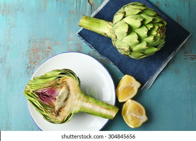 Artichokes on plate, on color wooden background