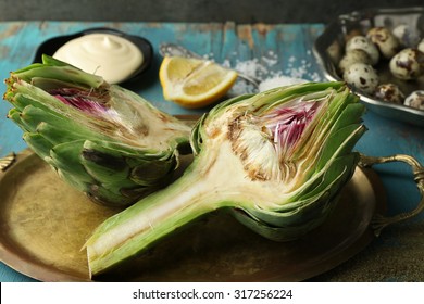Artichokes on tray, on color wooden background