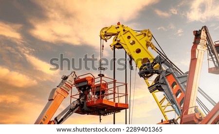 Articulated boom lift. Aerial platform lift and construction crane with sunset sky. Mobile construction crane for rent and sale. Maintenance and repair hydraulic boom lift service. Crane dealership.