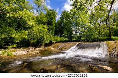 Artificial cascade and dam for old water mill in natural reserve “Hönnetal“ – Hoenne river canyon, Sauerland Germany. Sunny idyllic atmosphere near hiking trail from Hemer to Balve called “Waldroute“.