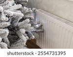 Artificial Christmas tree at home near heating radiator