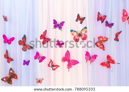 The artificial colorful butterflies on colorful curtain background. The butterflies fly one by one in a curve.