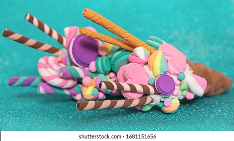 artificial dessert made of polymer clay. On a turquoise shimmering background. Ice cream in a waffle cone with marshmallows and macaroni.